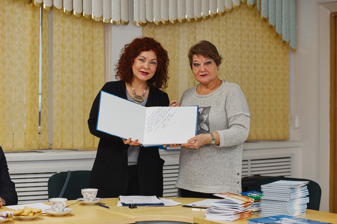 Автор-составитель Марина Чурилова передает экземпляр книги с автографом директора Сургусткого ЗСК